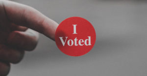 Finger with "I Voted" sticker.