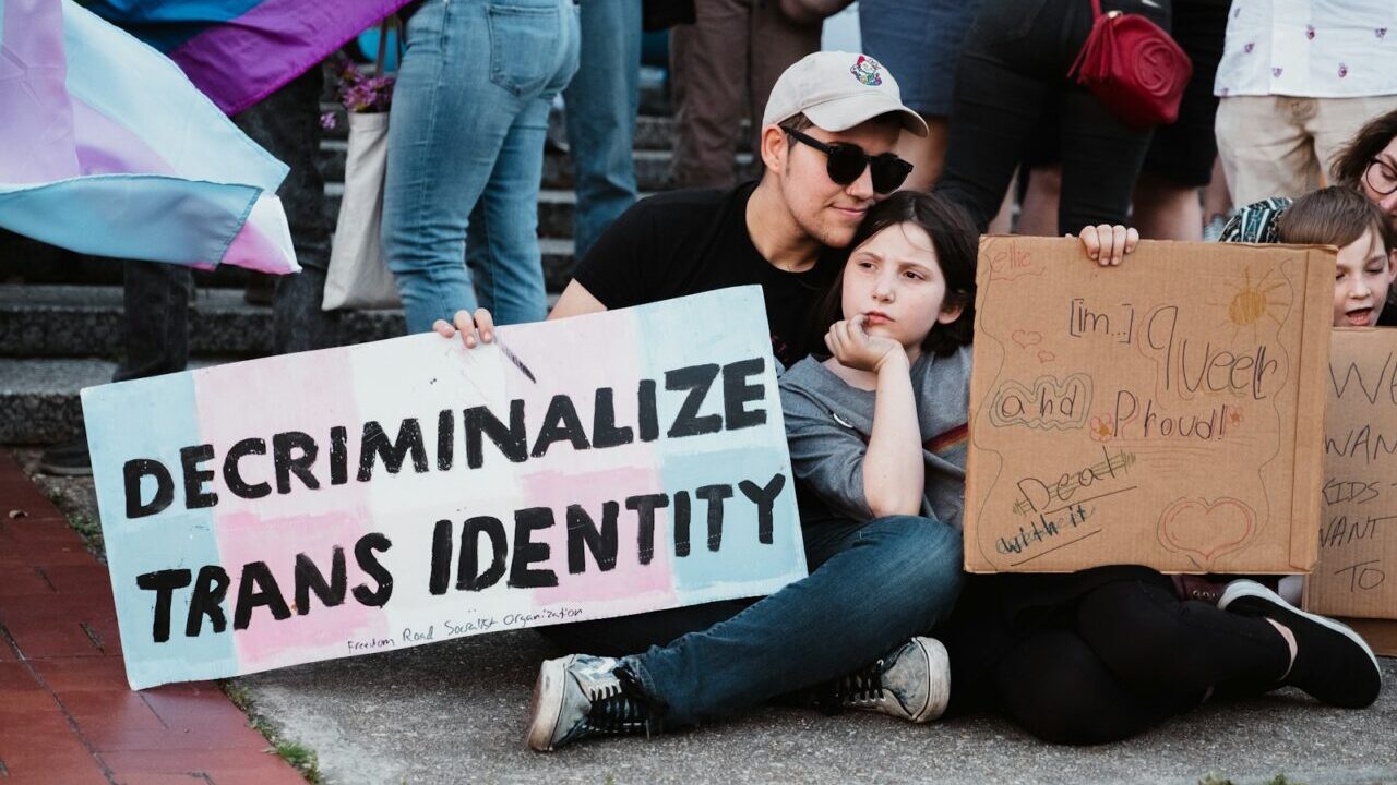 a group of people sitting on the ground holding signs