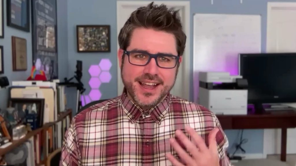 Joel McDonald, Chairperson of LGBT+ Democrats of Virginia, speaking into the camera wearing a red and white flannel button up shirt.